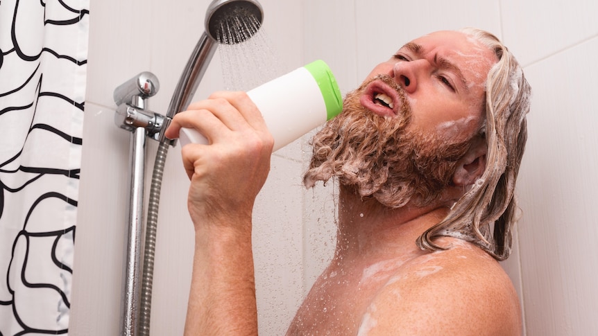 bearded man in the shower singing into shampoo bottle