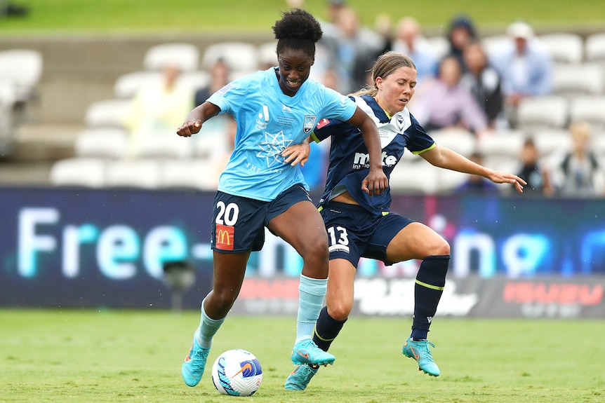 A Sydney FC player tries to hold off a Melbourne Victory opponent in the A-League Women grand final.