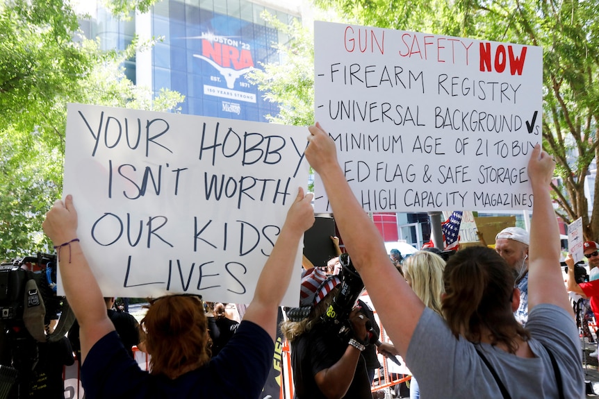 Sign reads your hobby isn't worth our kids' lives at protest outside NRA