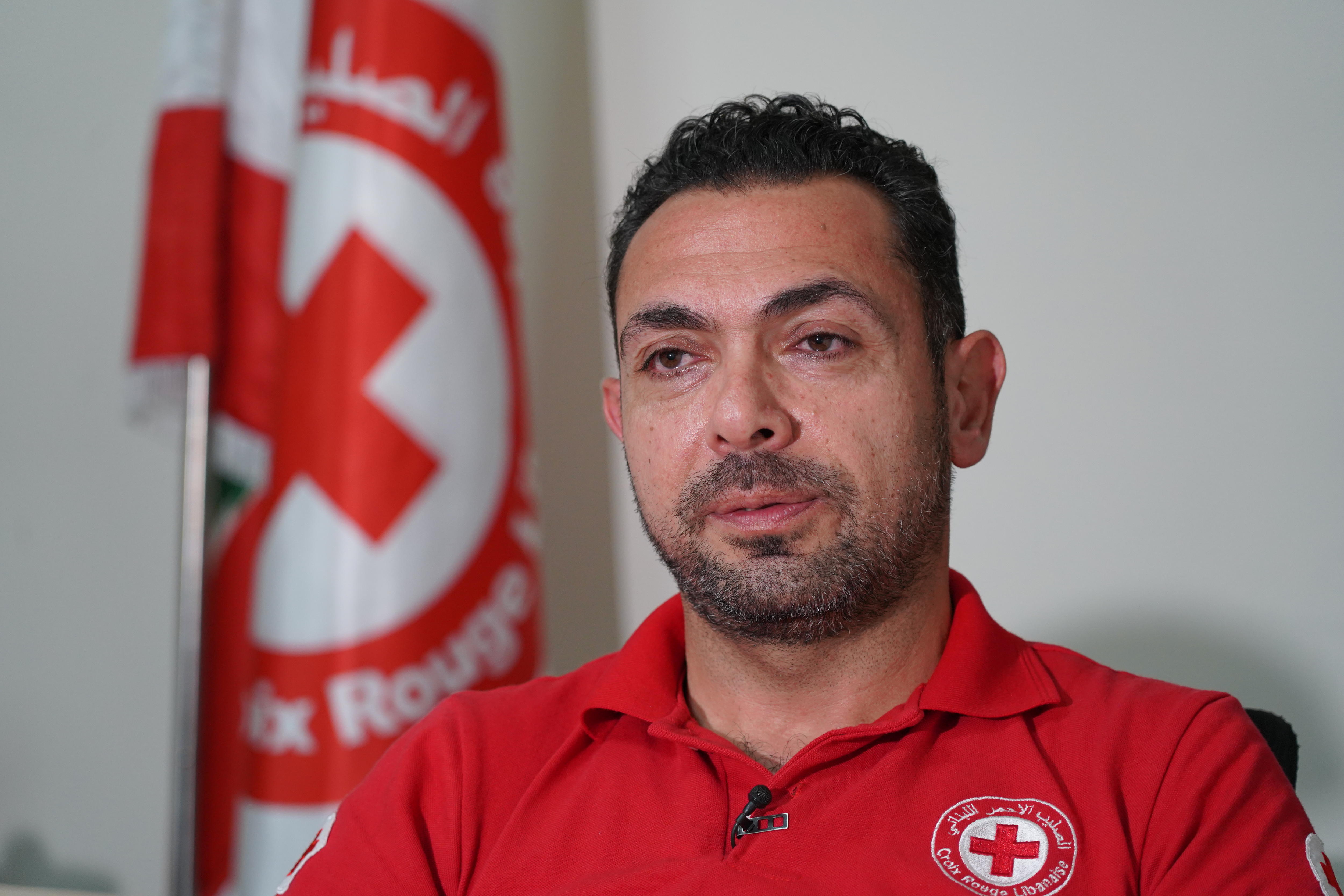 a portrait of a man in front of a red cross flag