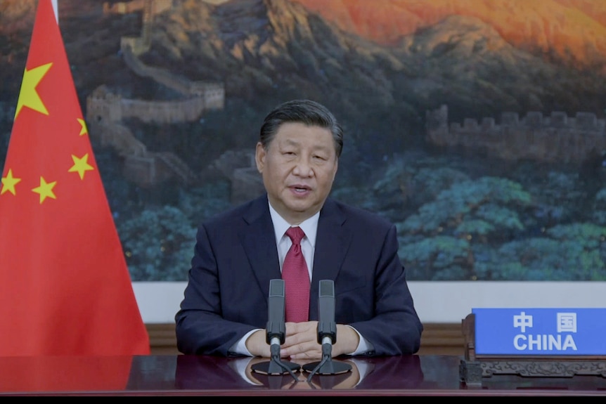 Chinese President Xi Jinping is seated beside a Chinese flag as he addresses the United Nations General Assembly