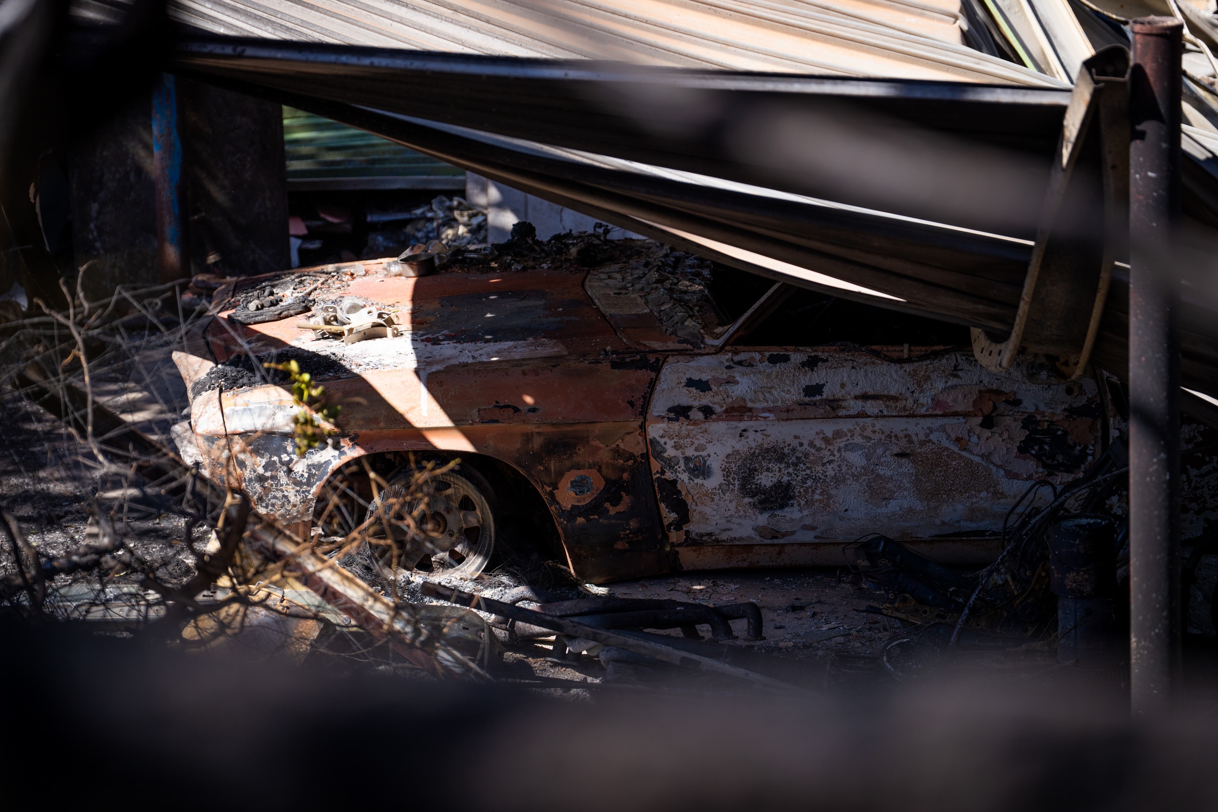 Un coche fue aplastado por chapa ondulada y ramas quemadas