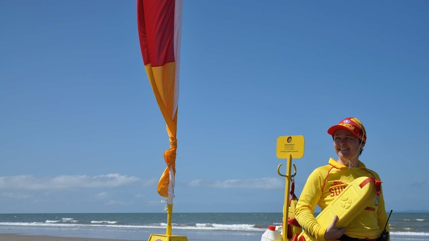 Kirsty Glithero, a surf lifesaver, holds a flotation device while standing next to a canoe on the beach.