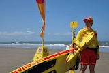 Kirsty Glithero, a surf lifesaver, holds a flotation device while standing next to a canoe on the beach.