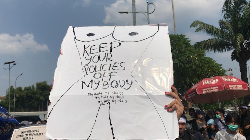 A protester holds a sign reading' 'Keep your policies off my body' and 'My body my choice'.