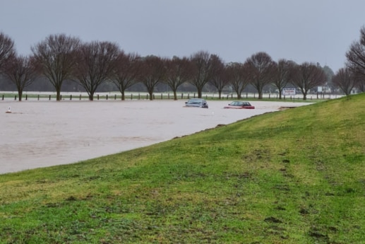 Cars stuck in water on a flooded road.