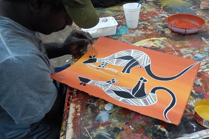 A man paints kangaroos