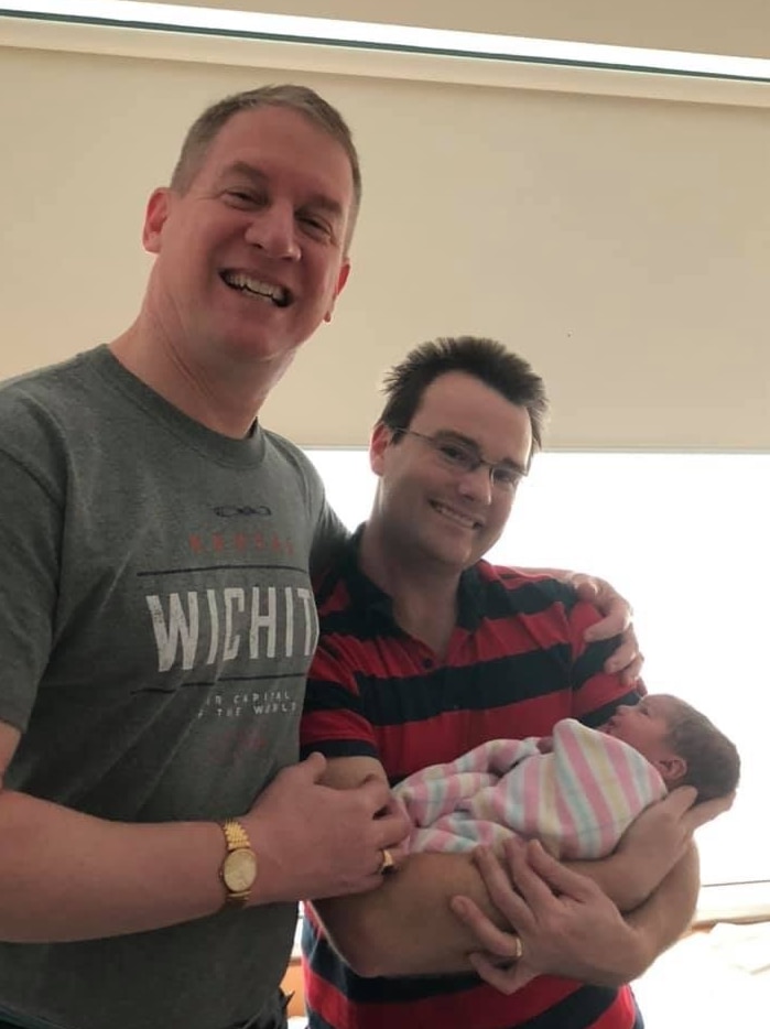 Two men smiling with a baby