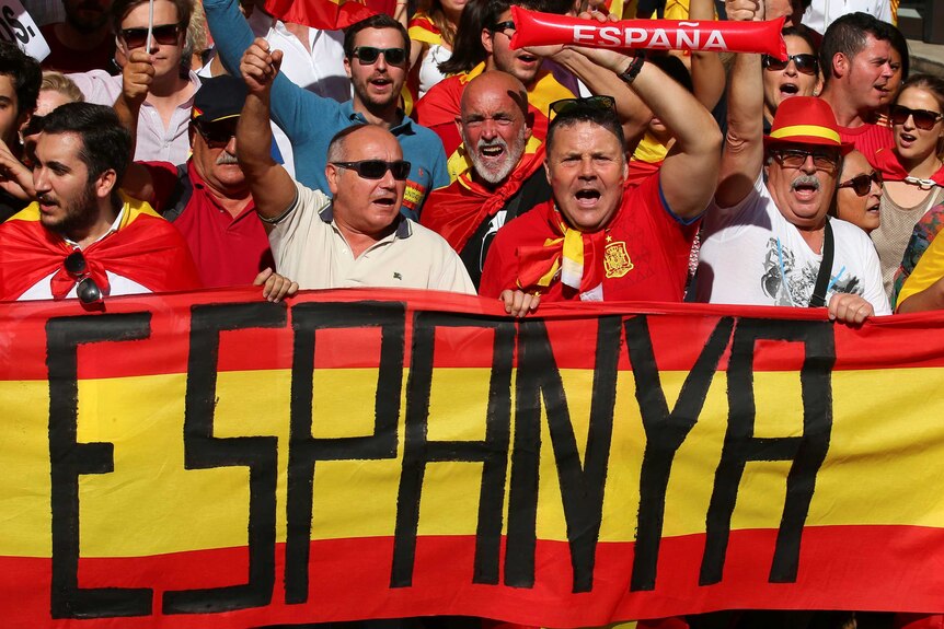 Demonstrators hold a sign saying "Espanya". They are dressed in red and yellow