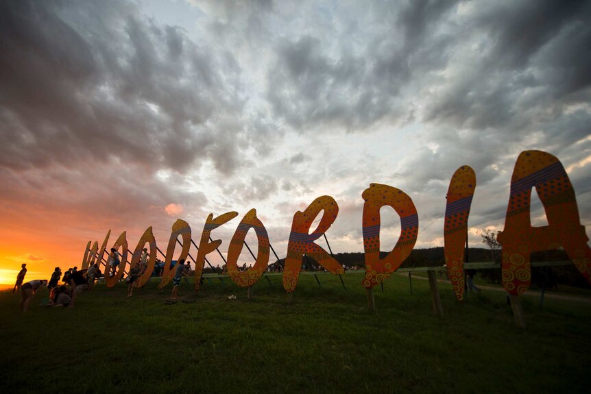 Large fabricated letters that spell out "Woodfordia" standing on a hill in low light.