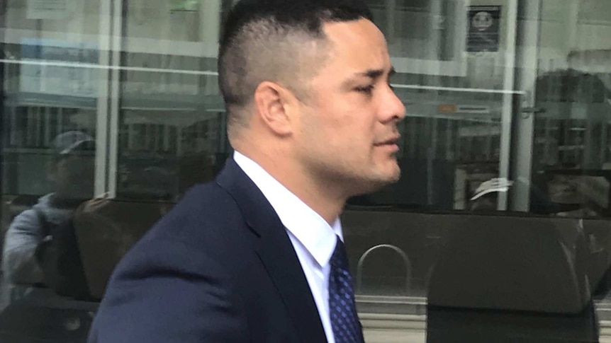 A man in a suit, seen in profile as he walks past a window.