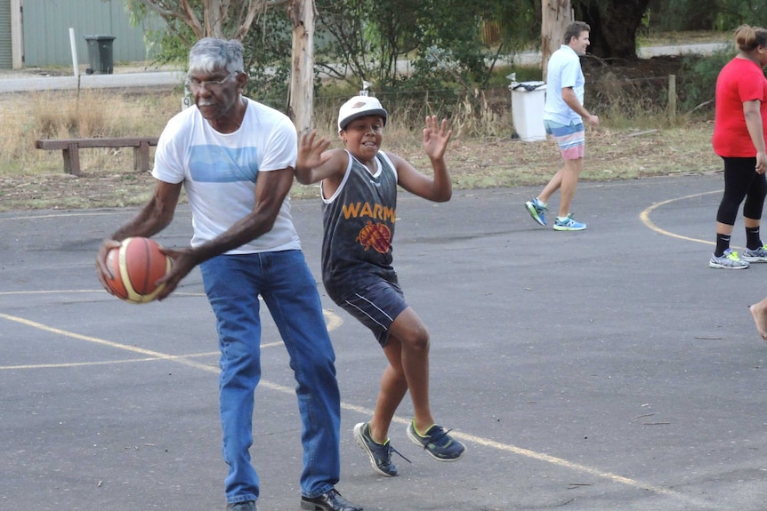 A young boy and an older man play basketball.