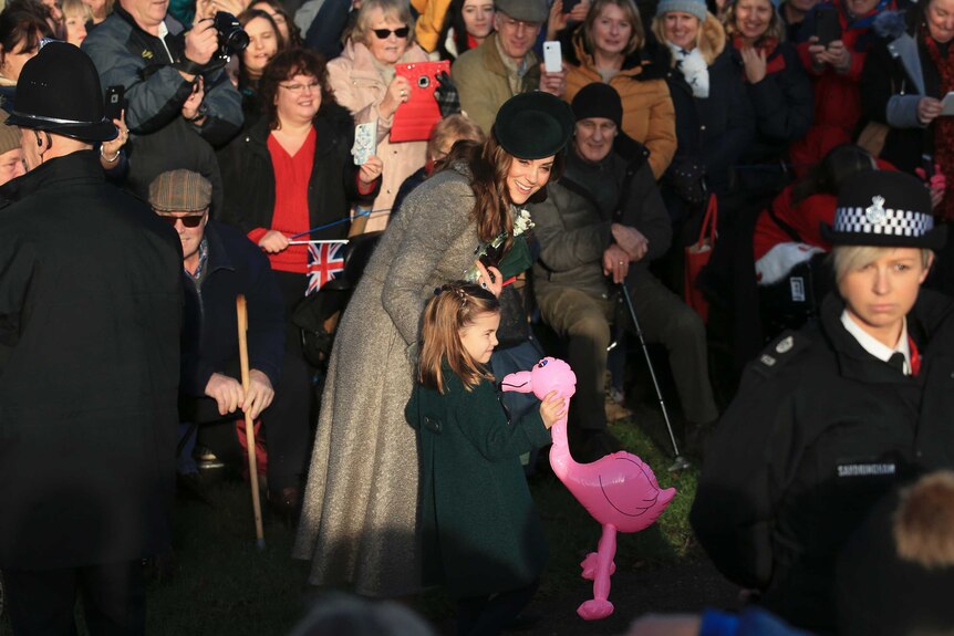 Britain's Catherine, Duchess of Cambridge, speaks with her daughter Princess Charlotte who is holding a pink flamingo toy.