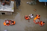 Aid workers deliver relief material using floatation devices in flood waters.