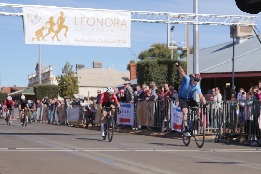 cheering cyclists ride cross the finish line