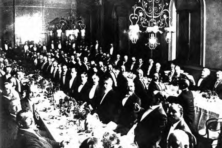 a black and white photo of many men in disguise at a dinner party