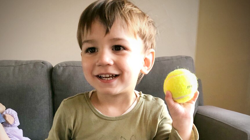 A young boy holds a tennis ball in his left hand, in a story about left-handedness revealing family history.
