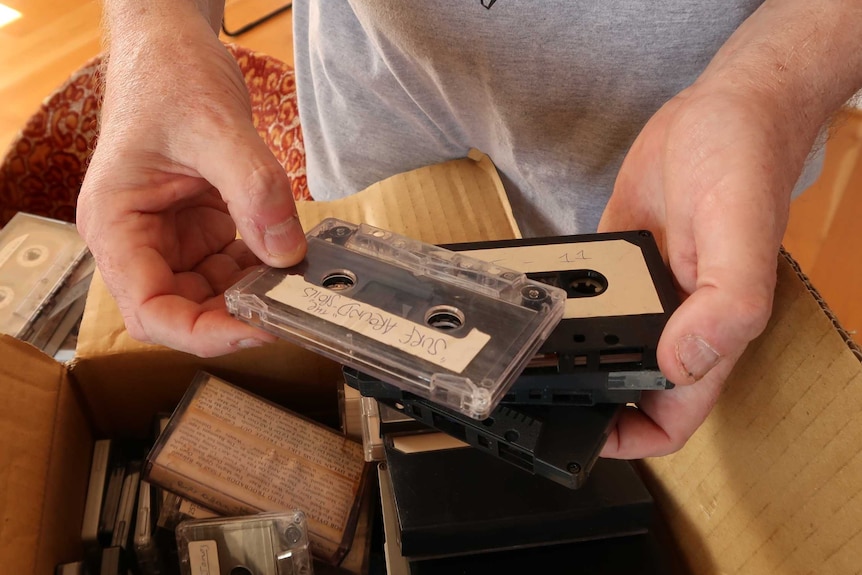 A man sorts through a box of old cassette tapes