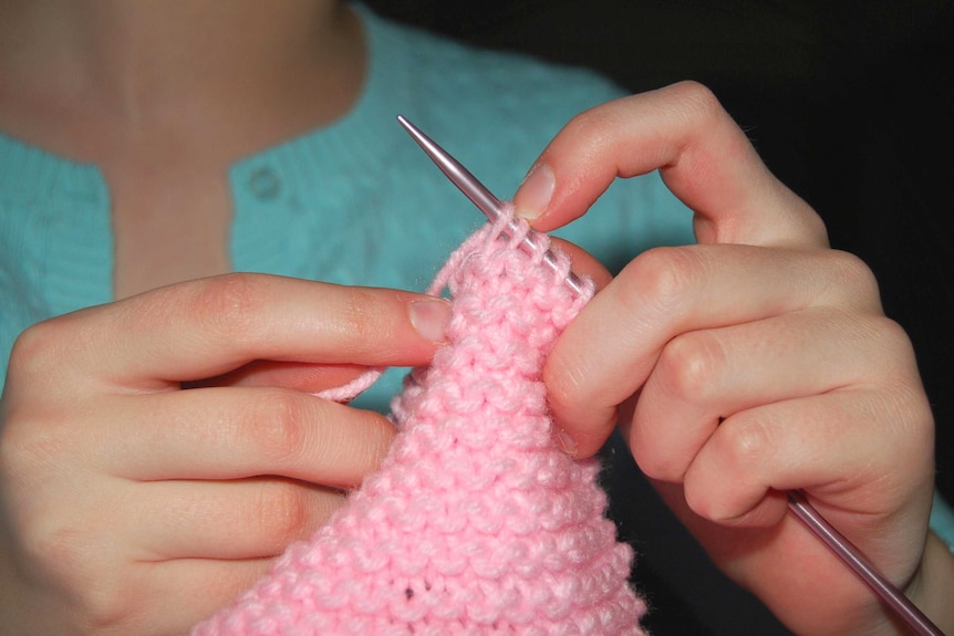 A woman knits.