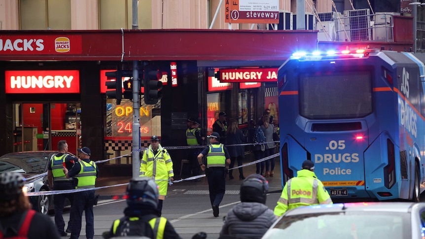 A drug testing bus and police tape is used to block Bourke Street.