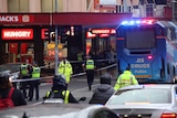 A drug testing bus and police tape is used to block Bourke Street.