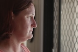 Woman looking out screen door with light on her face