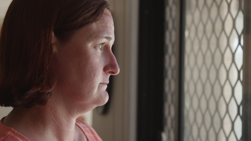 Woman looking out screen door with light on her face