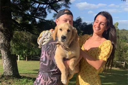 A young man and woman hold a puppy.