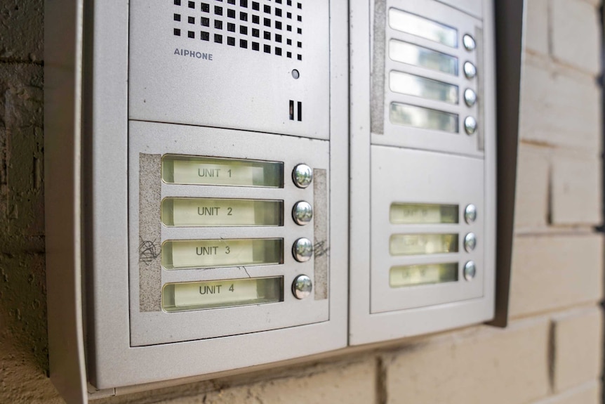 A close-up of a silver intercom for an apartment building, listing apartments one to four.