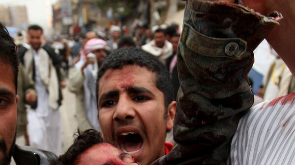 An anti-government protester yells as he carries a wounded demonstrator in Sanaa on March 18, 2011.