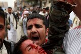 An anti-government protester yells as he carries a wounded demonstrator in Sanaa on March 18, 2011.