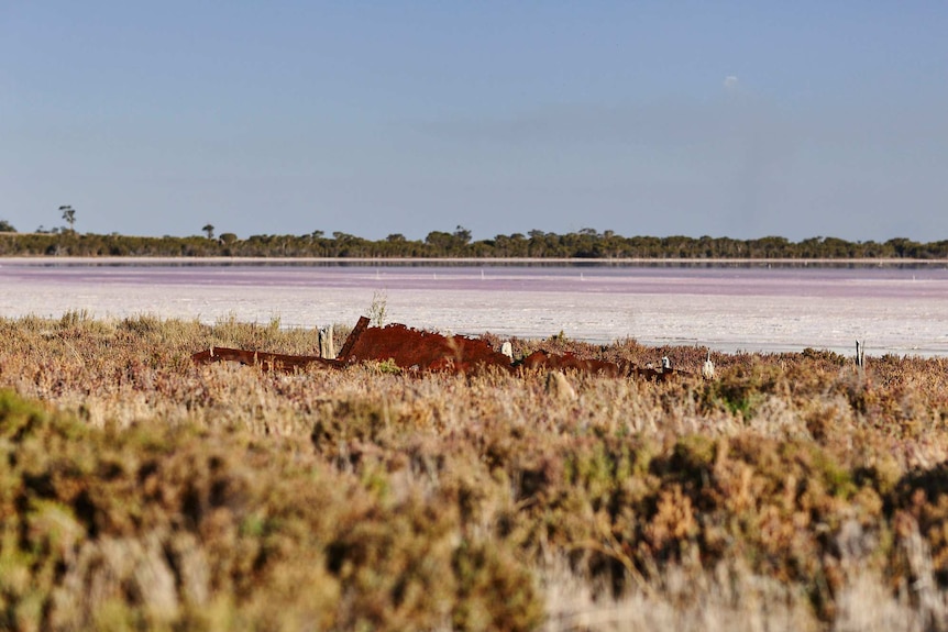 Rusted equipment sits on the edge of Pink Lake.