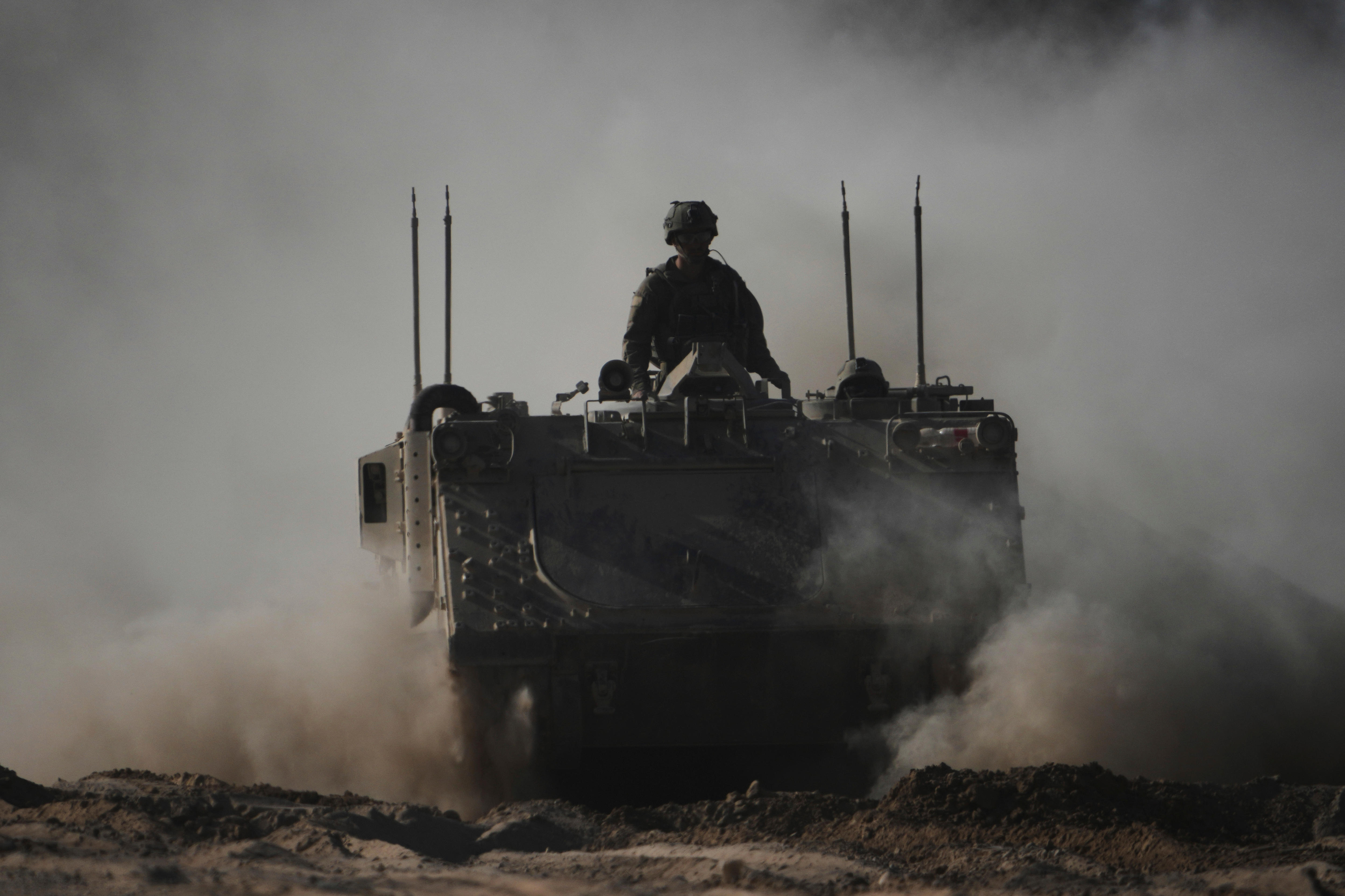 Israeli troops in armored personnel carrier kick up dust as they drive near the border with Gaza.