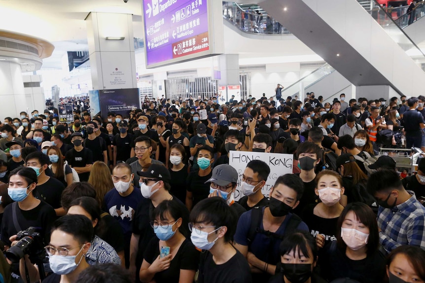 A group of young people standing together at the departures hall at Hong Kong airport