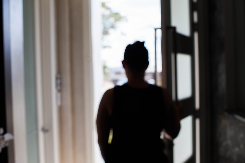 A woman's silhouette stands in a doorway
