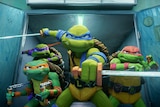 Four green cartoon mutant turtles burst through a set of doors, weapons drawn, including swords