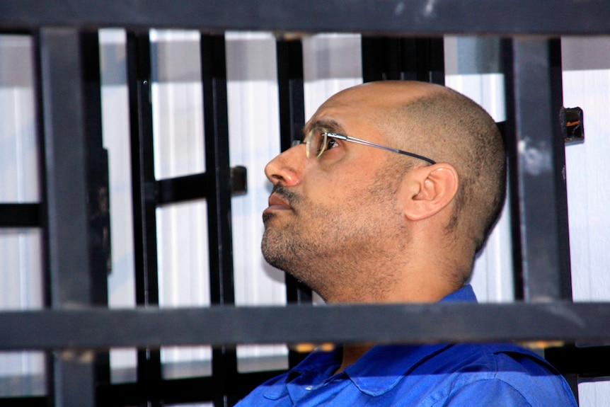 Saif al-Islam Gaddafi is seen through a barred witness box as he attends a hearing in Zintan, May 2014.
