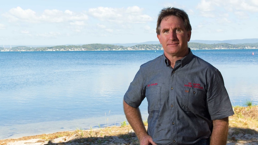 Des Maslen stands next to Lake Macquarie.