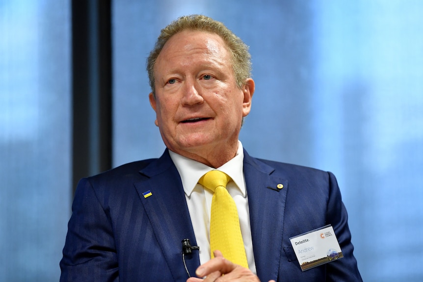 A man wearing a suit and yellow tie looking serious. 