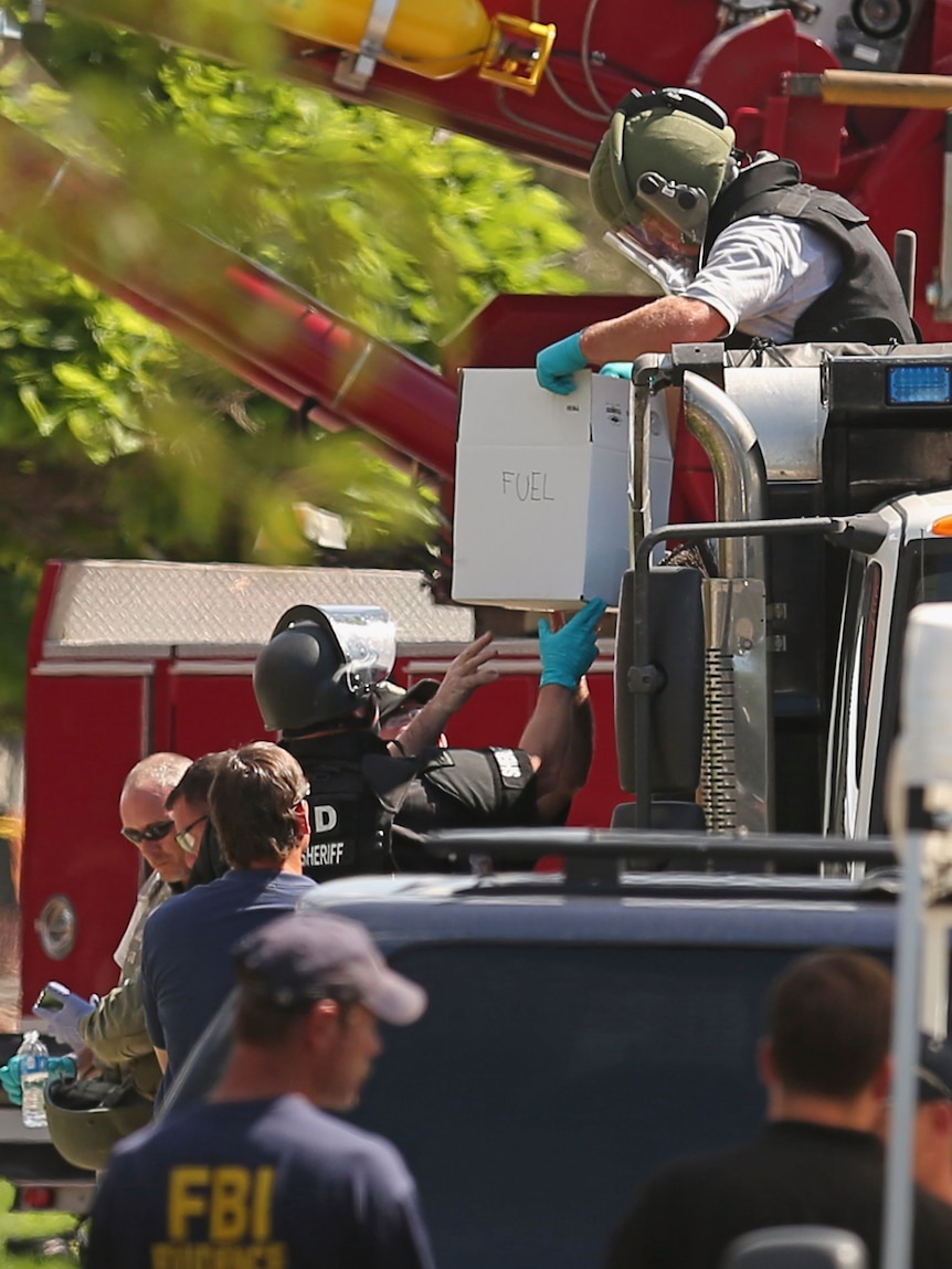 Experts load boxes of improvised explosive devices from James Holmes's apartment into a sand-filled dump truck.
