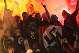 Russian football fans hold swastika flag at game.