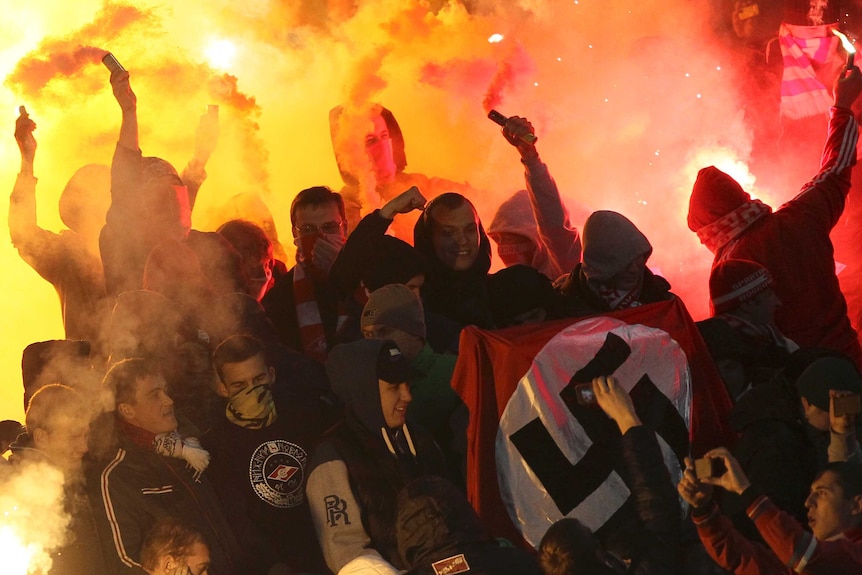 Supporters light flares and wave a Nazi flag