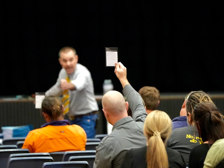 A man holding up a white bidding page 