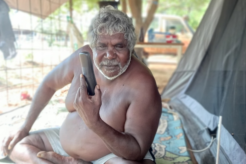 Djambawa Marawili AM showing off the new effective land-line phone connected to his tent-house house at Baniyala.