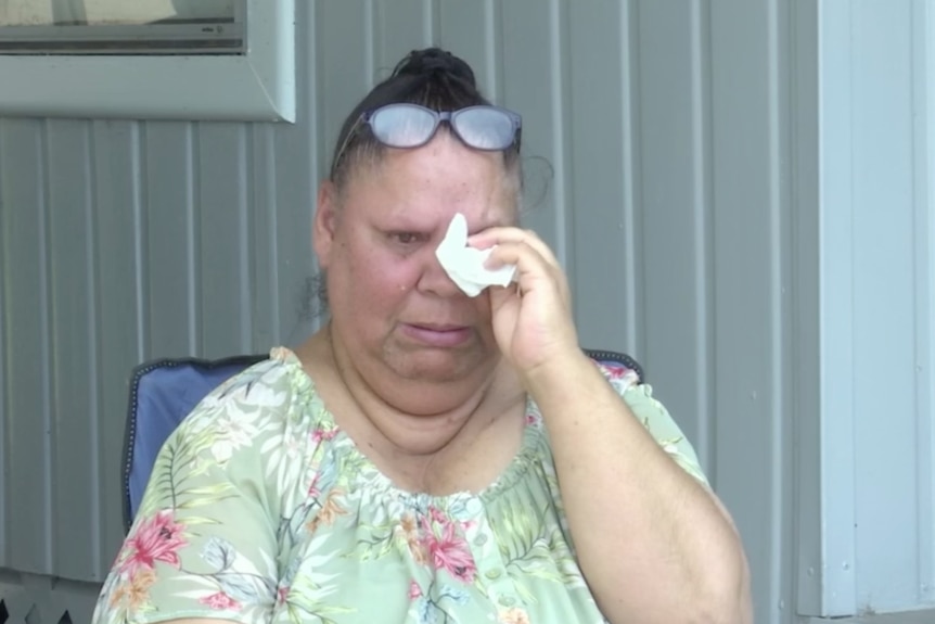An Indigenous woman cries and wipes her eye with a tissue