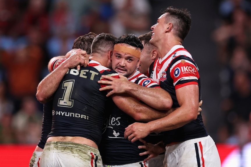 A man embraces his teammates after scoring a try