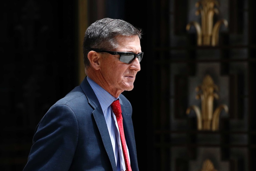 Michael Flynn departs a federal courthouse wearing sunglasses and a blue suit.