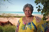 Venessa Poelina stands on the beach in Broome. She stares into the camera.