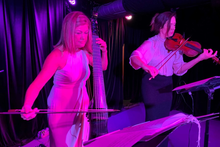 Two women play the violin and chello on stage