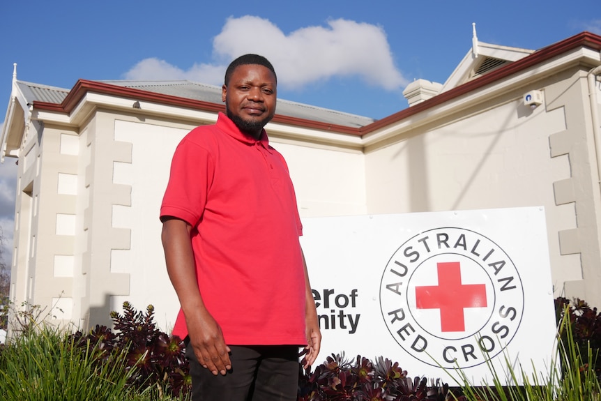 A man in a red shirt smiles at the camera.